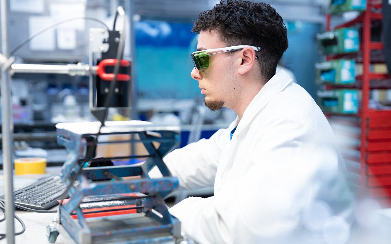 Industrial photography Saarland: lab technician with safety glasses at a test rig