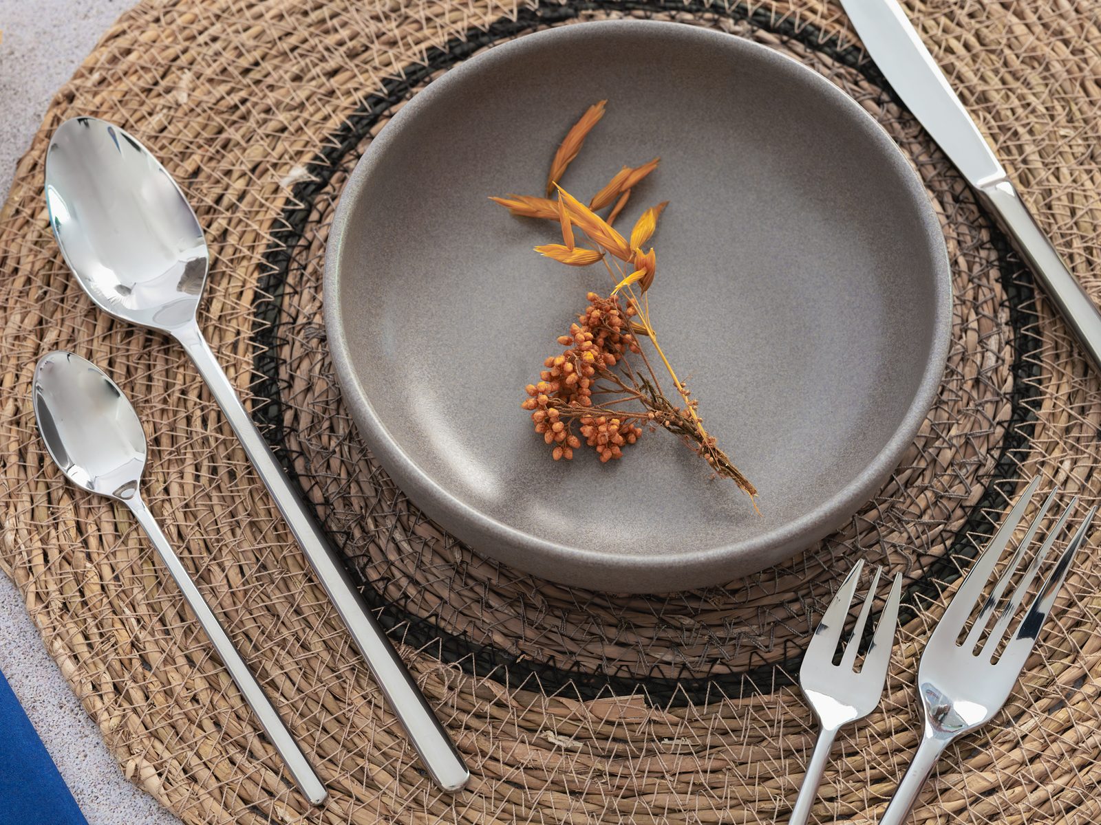 Produktfotografie Tischkultur: Besteck und Steingutteller auf Rattan-Platzset