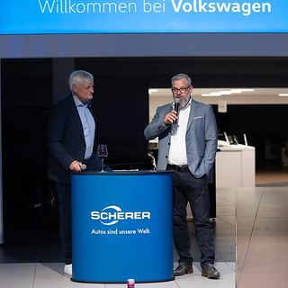Eventfotografie Saarland: Begrüßungsrede mit Mikrofon bei einer Veranstaltung im Autohaus