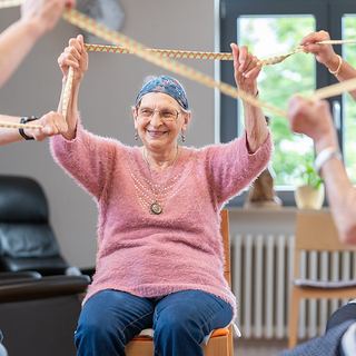Praxisfotografie Saarland: Seniorin bei einer Bewegungsübung in der Gruppe