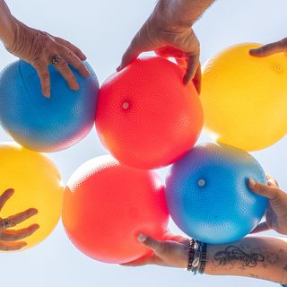 Praxisfotografie Saarland: Hände halten bunte Bälle in einer Bewegungsgruppe