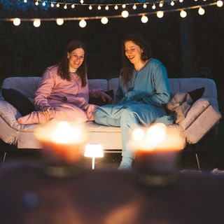 Werbefotografie Saarland: Zwei Frauen auf einem Outdoor-Sofa bei Kerzenlicht und Lichterkette