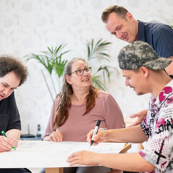 Praxisfotografie Saarland: Gruppenarbeit am Tisch mit Betreuer in einer Einrichtung