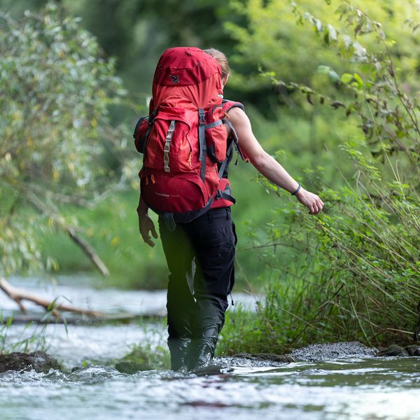 Werbefotografie Saarland: Wanderin mit rotem Rucksack im Bach