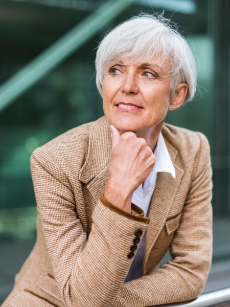 Portrait of senior businesswoman leaning on railing in the city looking around